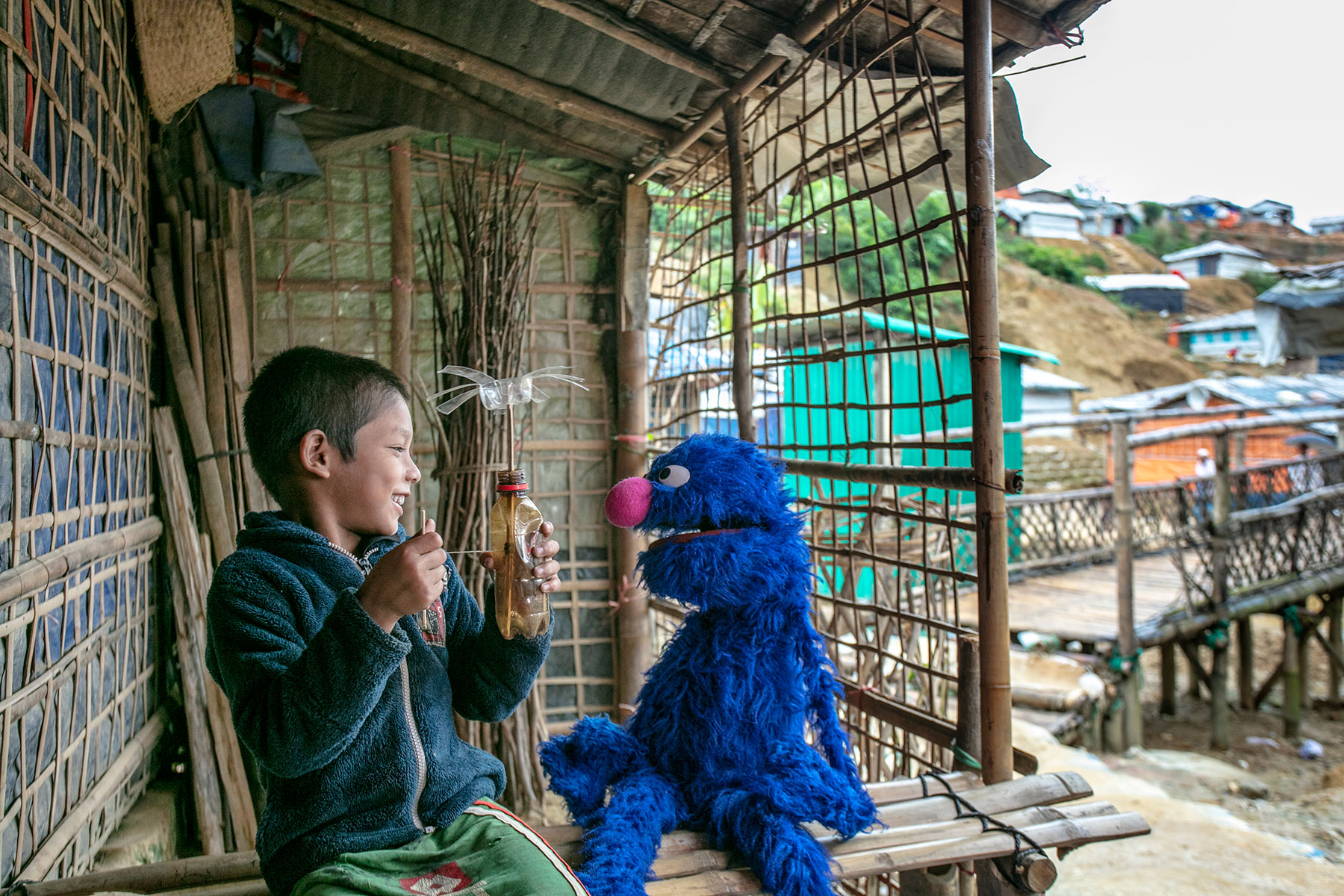 A Rohingya child plays with a muppet. Photo by Ryan Donnell for Sesame Workshop.