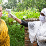 A BRAC community health worker checks a patient's temperature