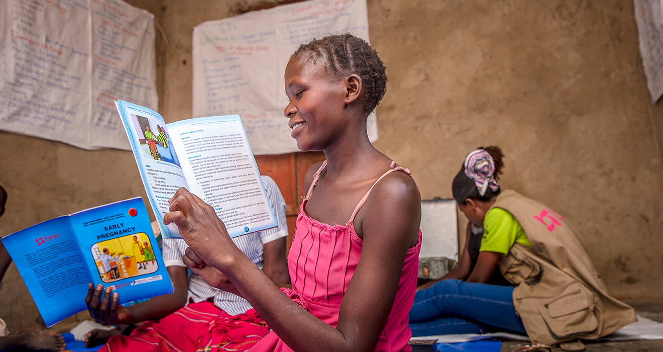 A girl in an ELA club in Uganda reads a book