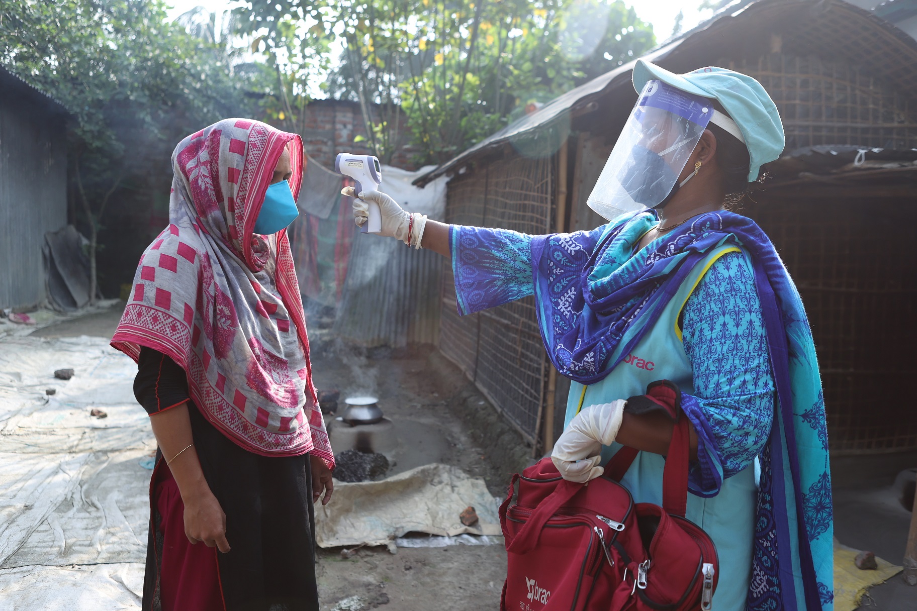 Community health worker checks temperature of patient.