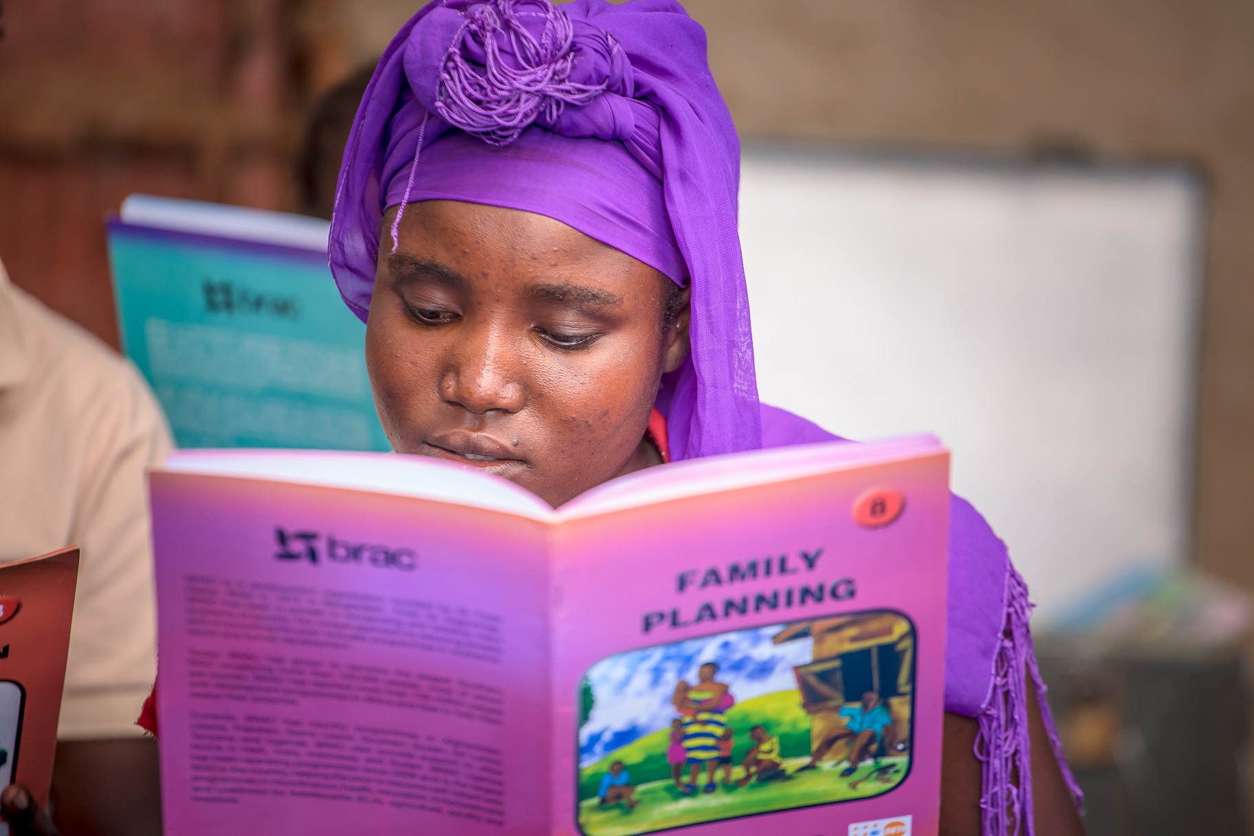 A girl in Uganda reads a new book about empowerment from BRAC.