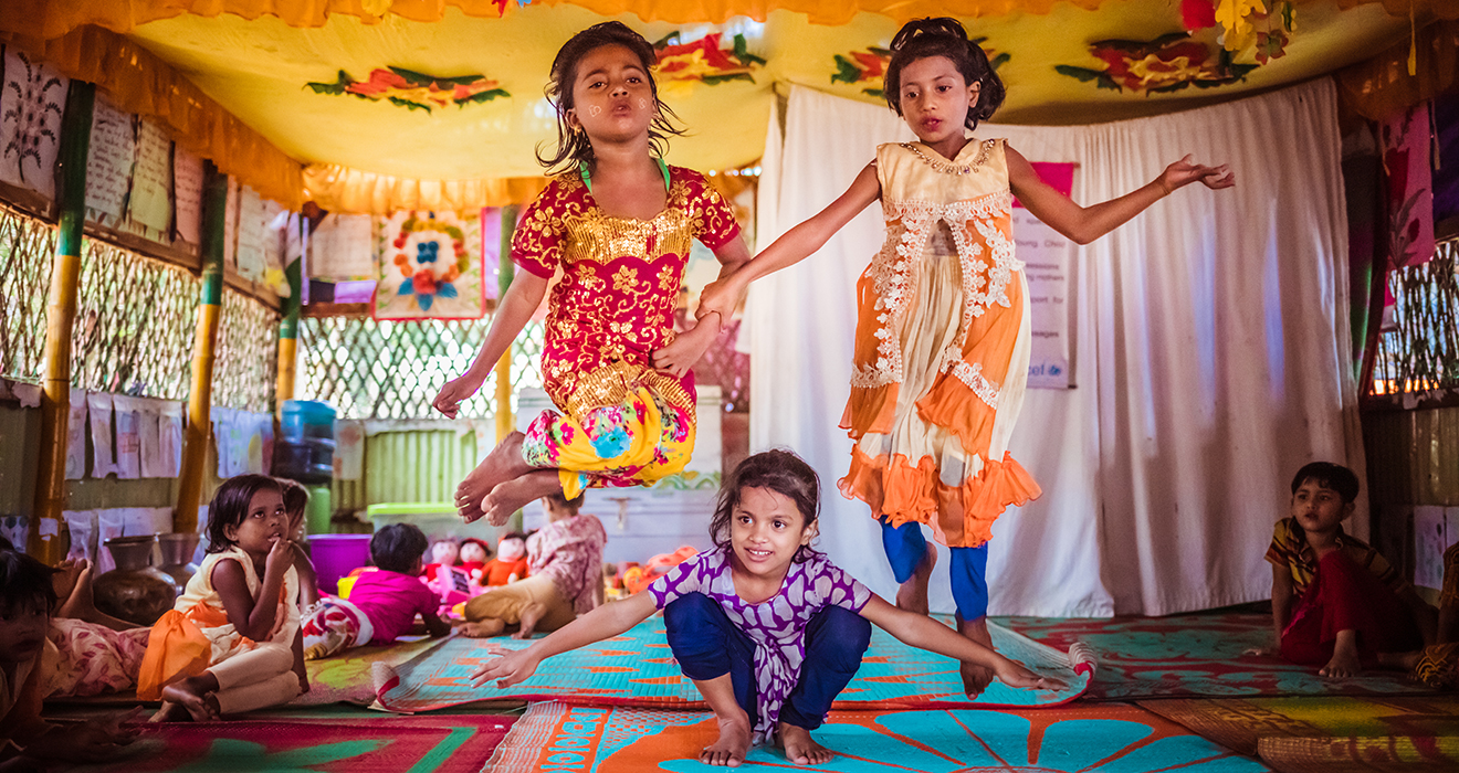 Three children jump up and down while playing a game in a Play Lab in Bangladesh