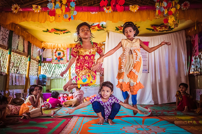 Three children jump up and down while playing a game in a Play Lab in Bangladesh