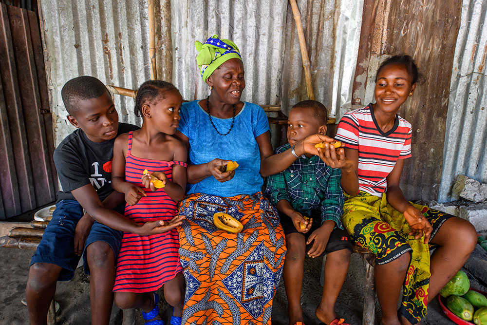 Photo by Alison Wright. A grandmother, who is a participant in BRAC's Ultra-Poor Graduation program, slices and shares a papaya with her four grandchildren.