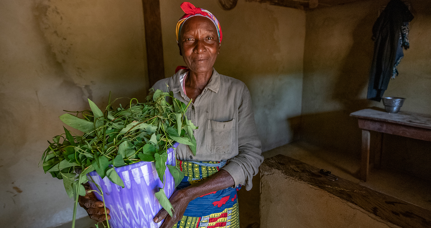 Lucy holds a bundle of produce from her kitchen garden while in her home