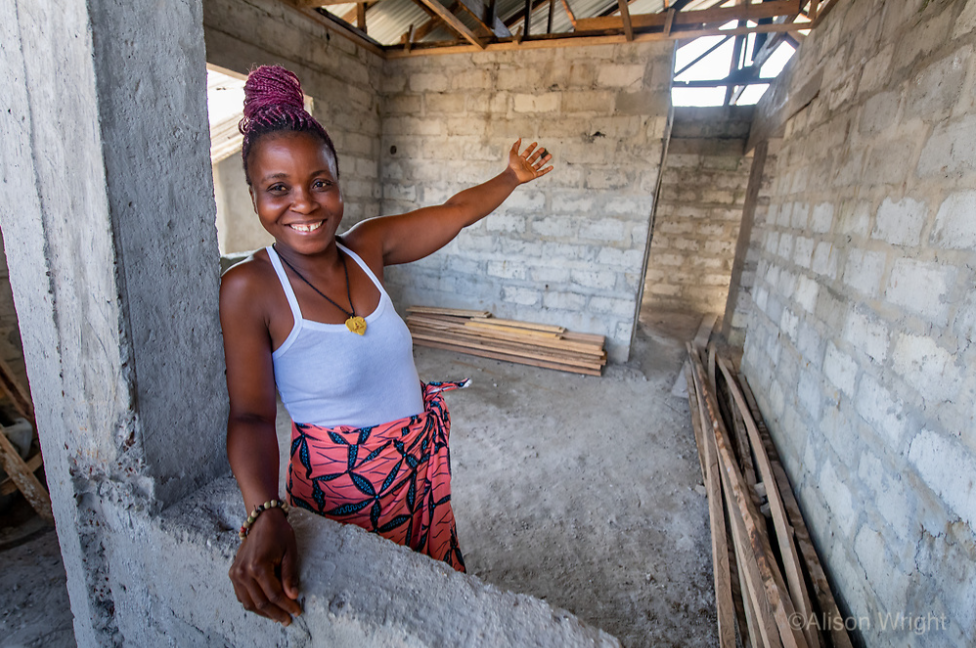 Jebbeh gestures to her new concrete block home which is under construction.