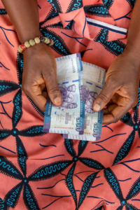 A closeup of Jebbeh's hands counting money at a microfinance borrower group meeting. Photo by Alison Wright.