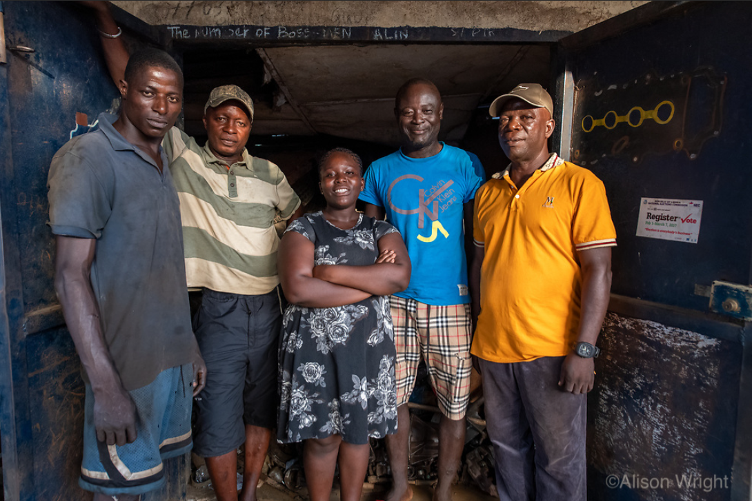 Josephine poses alongside four of her colleagues at the auto shop. She is notably the only woman in the group of five, and stands confidently in the middle with her arms crossed. Photo by Alison Wright.