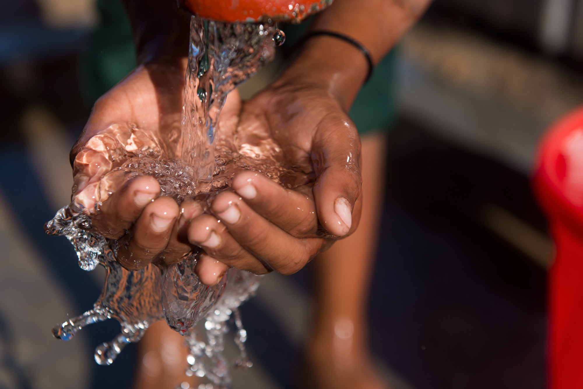 A close up of hands catching clean water from a spout