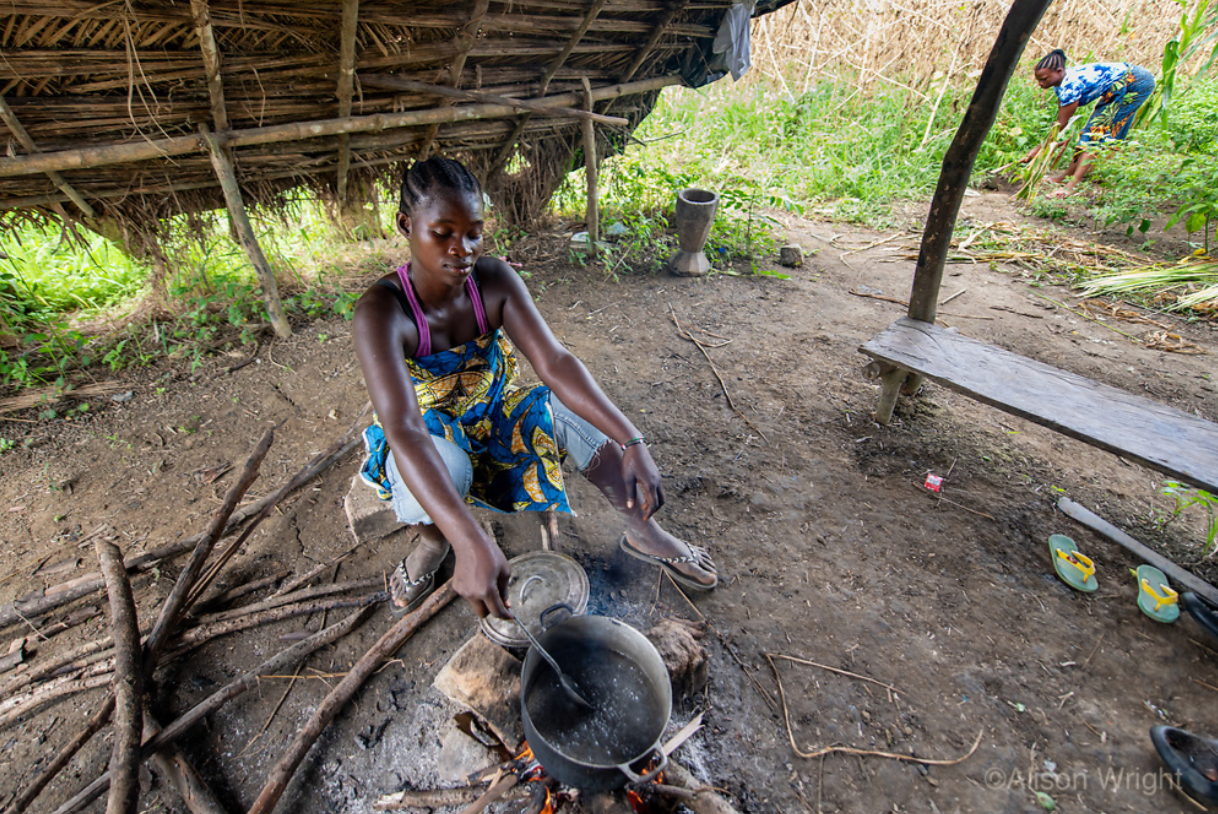 Patience cooks lunch under a shelter in the fields