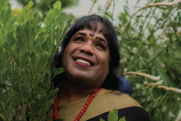 A closeup of Cynthia smiling as she stands in the outside in the trees