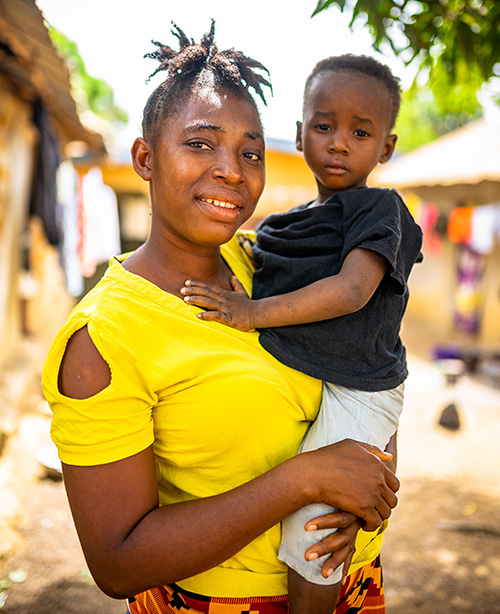 Adama poses while holding her young son.