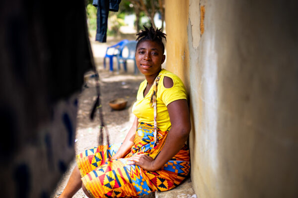 Adama sits outside of her home