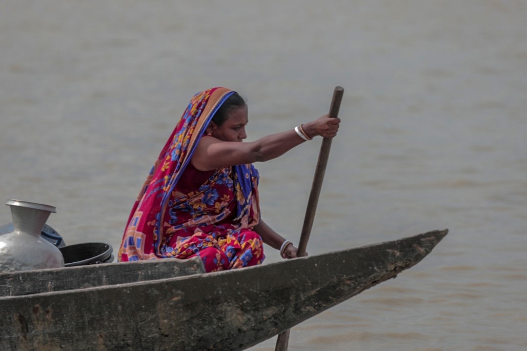 A woman living in a flood-prone area of Bangladesh paddles a small boat.
