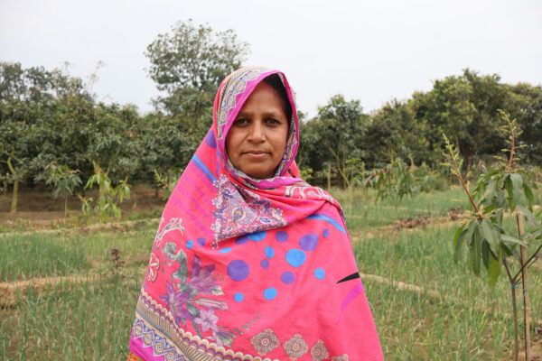 Marjina, a farmer in Bangladesh, poses in front of her land.