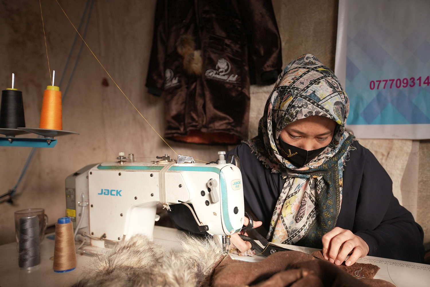 Zainab, a tailor in Afghanistan, sews a coat at her sewing machine.