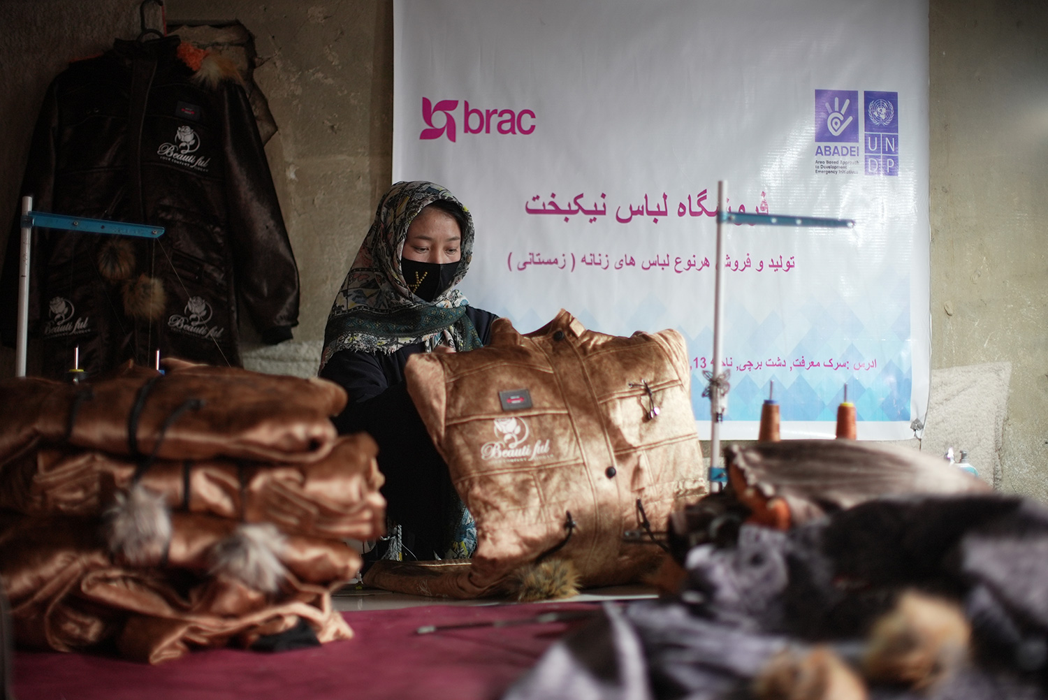 Zainab, a tailor in Afghanistan, inspects one of her coat creations.
