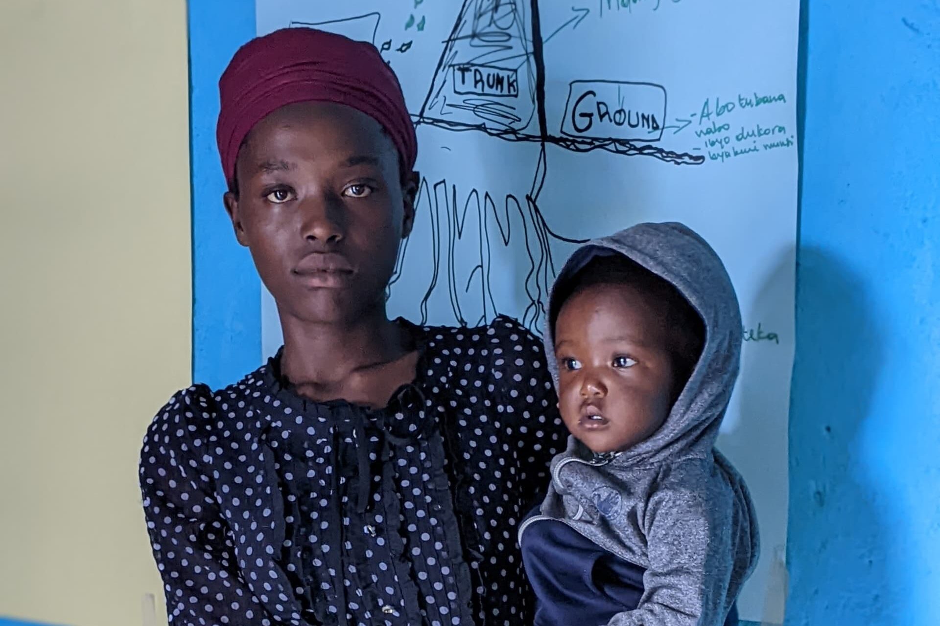 Esther, a BRAC participant and young mother, poses with her son at a BRAC youth empowerment club in Rwanda.
