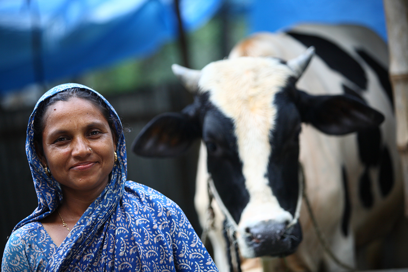 A woman in Bangladesh poses with her cow