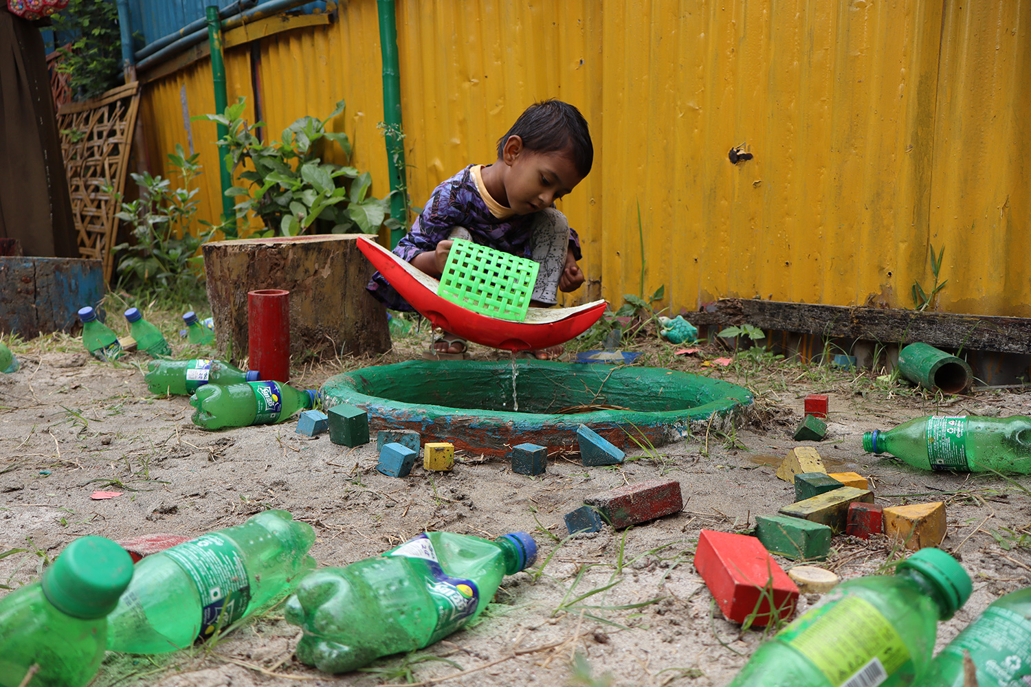 A boy in a Play Lab in Dhaka plays with water toys outside.