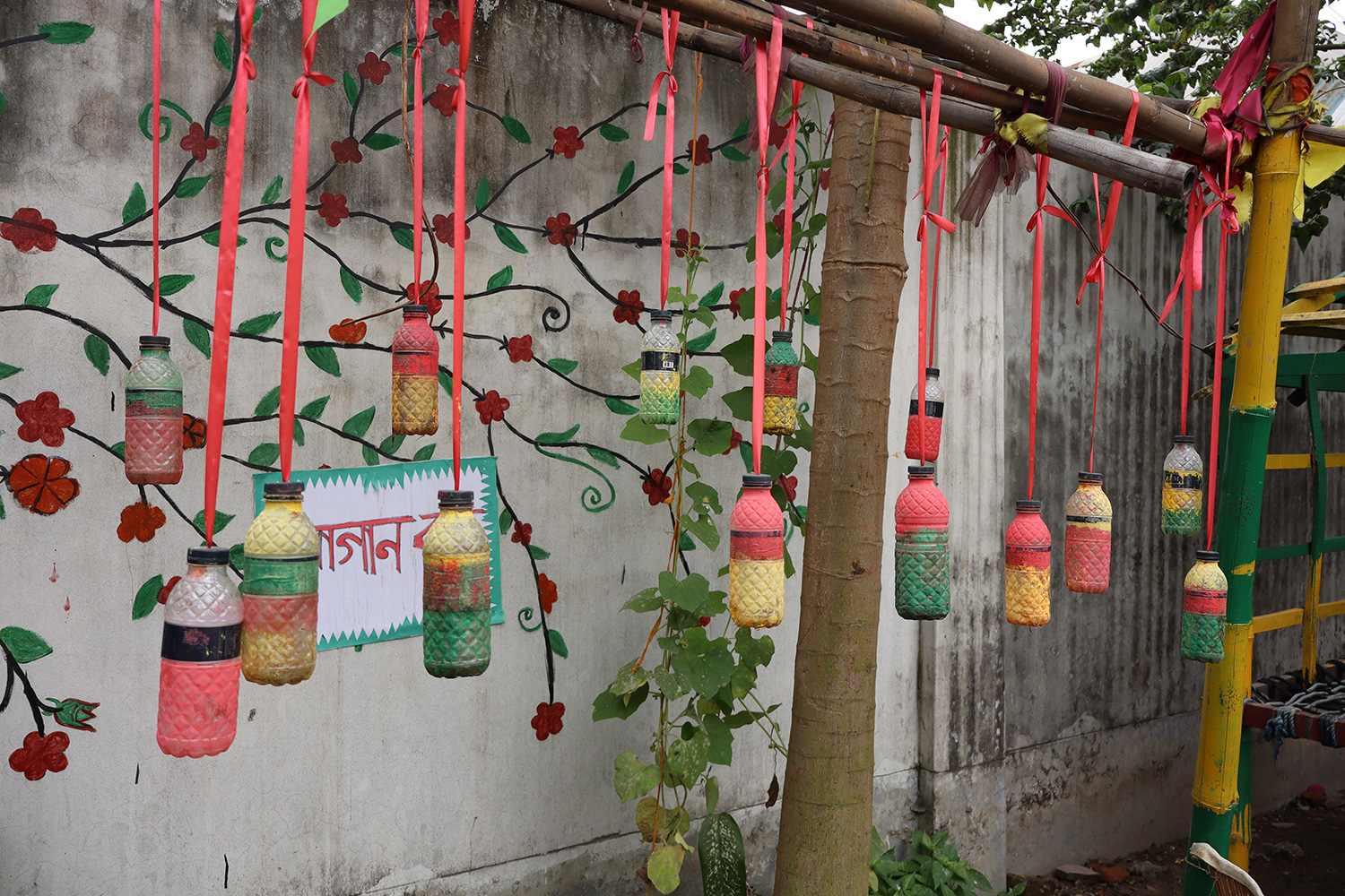Outside a Play Lab in Dhaka, colorfully painted decorations made from water bottles and other recycled materials hang from the building.