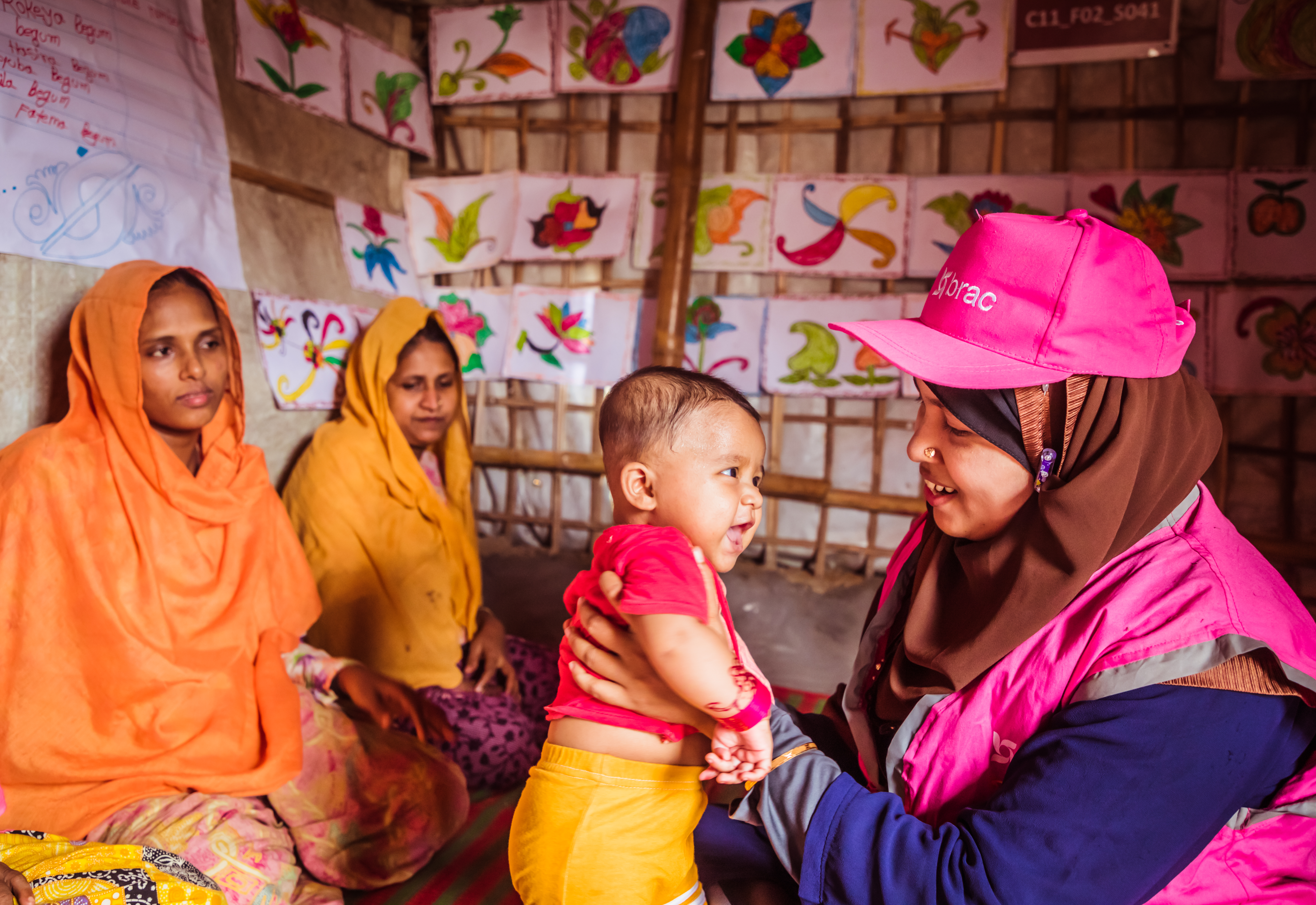 A community health worker in the Rohingya refugee camp holds a happy refugee baby