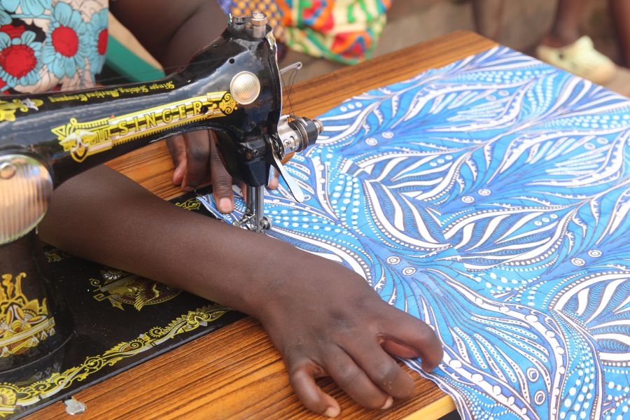 A close up of a woman's hands sewing colorful fabrics on a sewing machine.