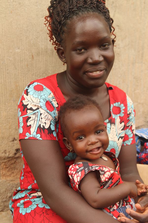 Lonah smiles while she holds her beaming young daughter in her arms.