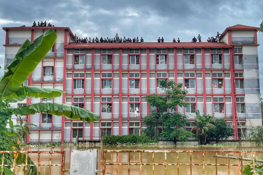 August 24, 2024: Dozens of people affected by flooding in Bangladesh look out from the rooftop of a multi-story building as rising floodwaters trap them from below and ominous skies linger above. 