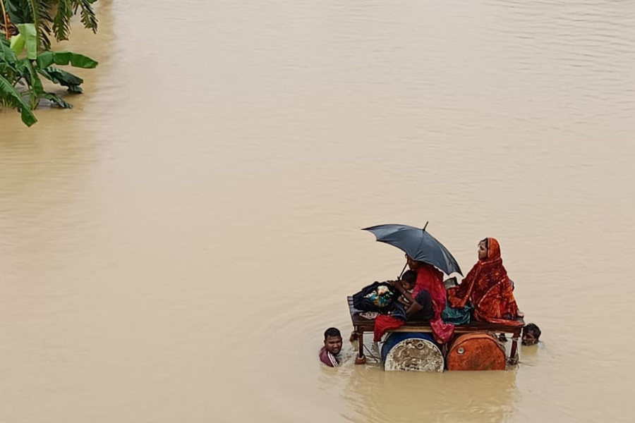 Two women float on top of a structure as two men attempt to swim them to safety through the floodwaters.