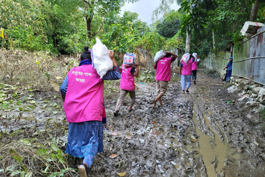 August 26, 2024: A BRAC team trudges through the mud in flood-stricken Chittagong, Bangladesh to deliver aid packages containing food and supplies to victims of the emergency. BRAC has launched a rapid needs assessment to ensure that efforts are reaching those who need it most. 