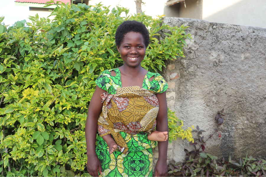 Angelique is all smiles as she poses outside in front of greenery.