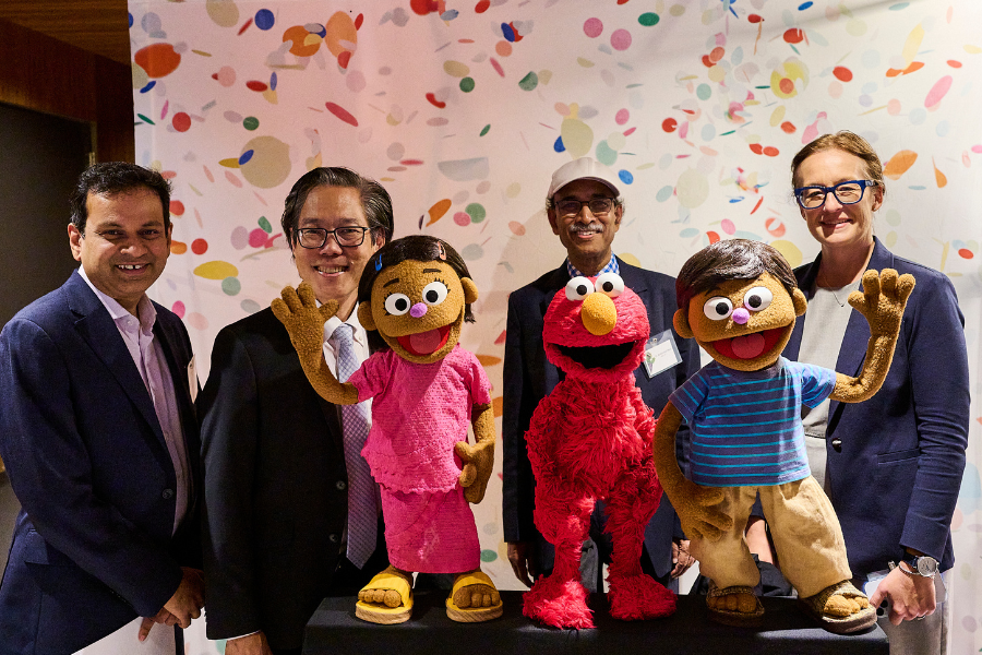 Four leaders from BRAC and NYU Global TIES for children pose with muppets at the Play to Learn event.