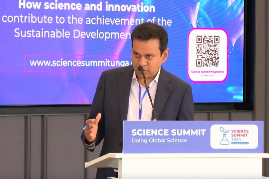 Asif Saleh, Executive Director of BRAC, speaks into a microphone while standing at a podium at the Science Summit.