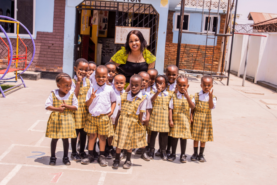 Queenfrida smiles and poses with a group of children from the day care she runs. 