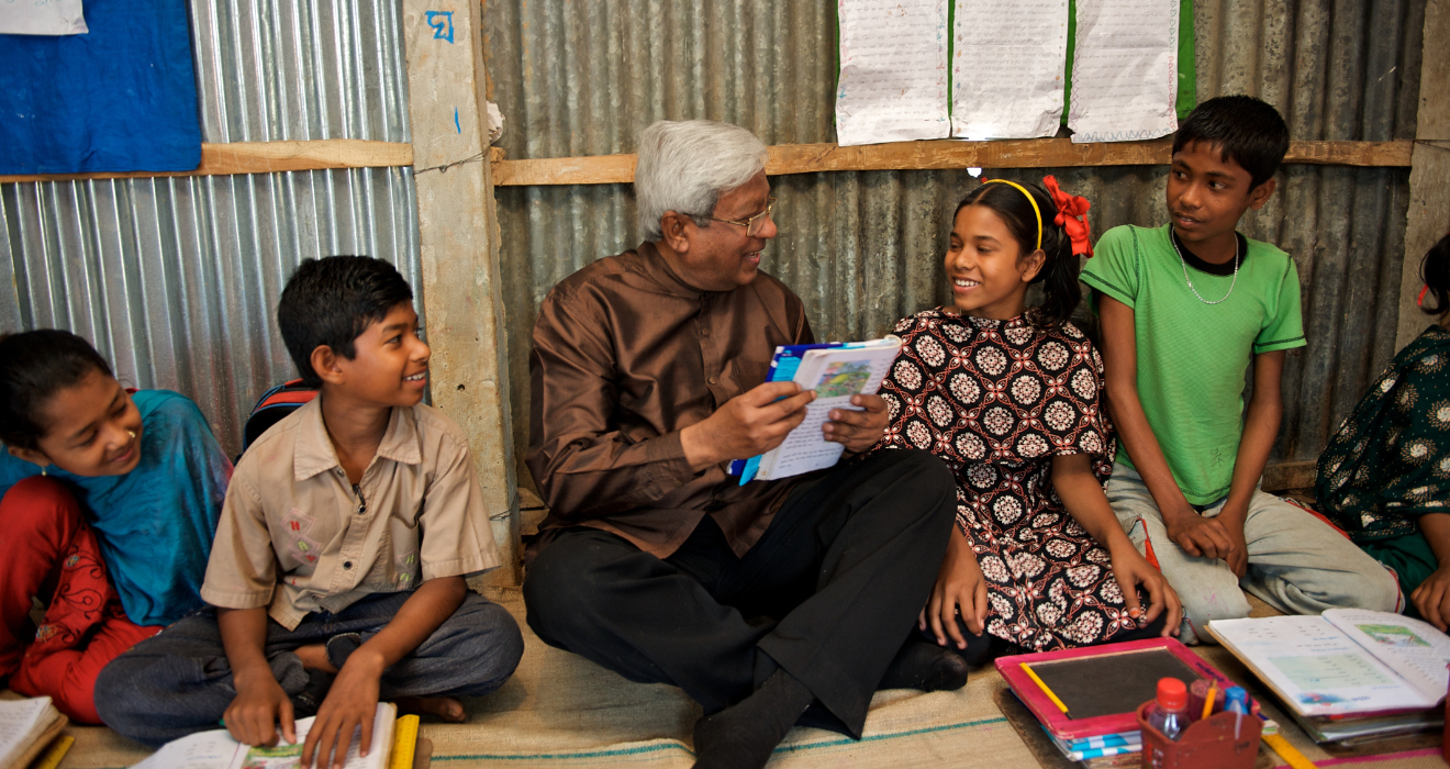 BRAC founder Sir Fazle Hasan Abed reads to a group of four children in a BRAC primary school in Bangladesh.