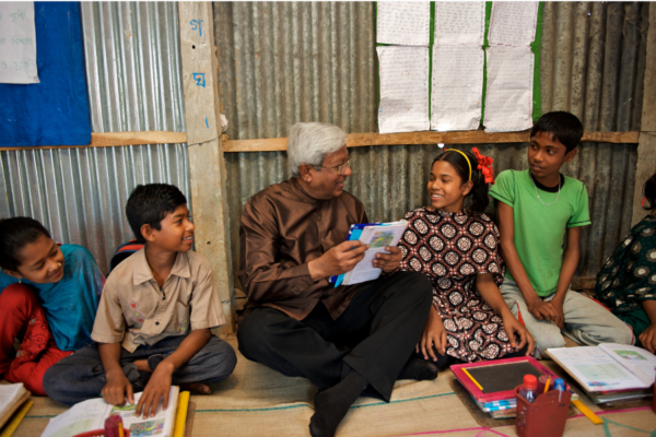 BRAC founder Sir Fazle Hasan Abed reads to a group of four children in a BRAC primary school in Bangladesh.