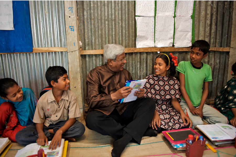 BRAC founder Sir Fazle Hasan Abed reads to a group of four children in a BRAC primary school in Bangladesh.