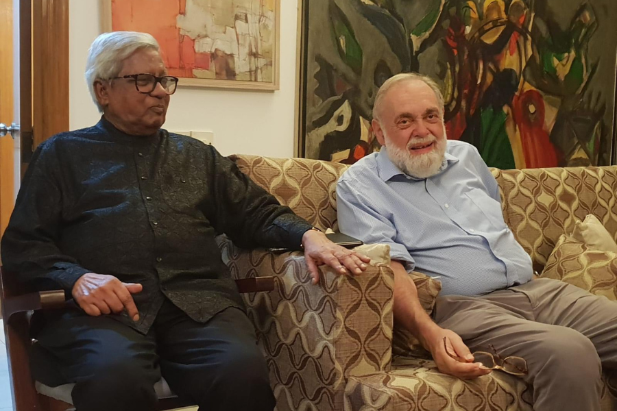 Dr. Richard cash, right, sits on a chair next to BRAC Founder Sir Fazle Hasan Abed, left, as they both smile.