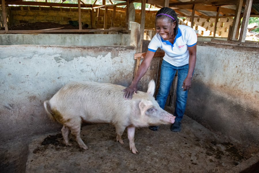 Selena stands in her pig pen and smiles while petting one of her pigs.