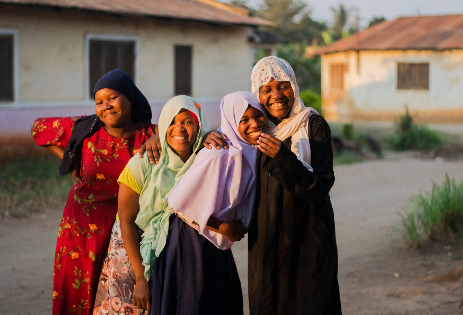 A group of four young women in a BRAC youth empowerment club in Tanzania smiling and posing.