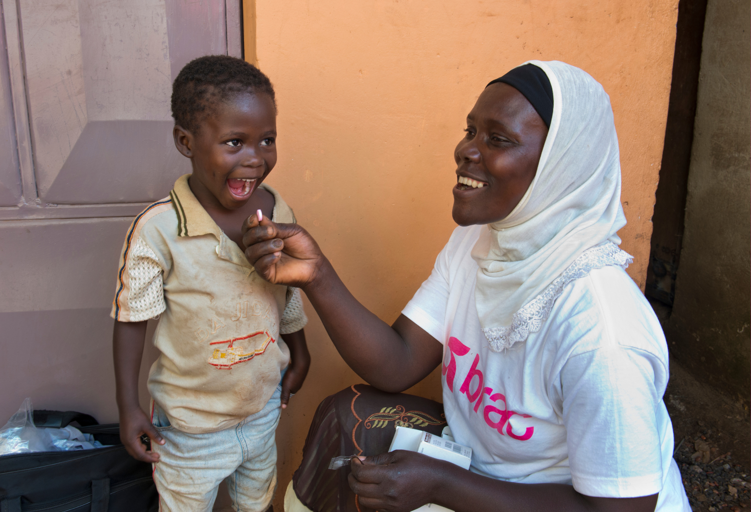 Image of a woman community health worker providing a medication to a young boy in Uganda.