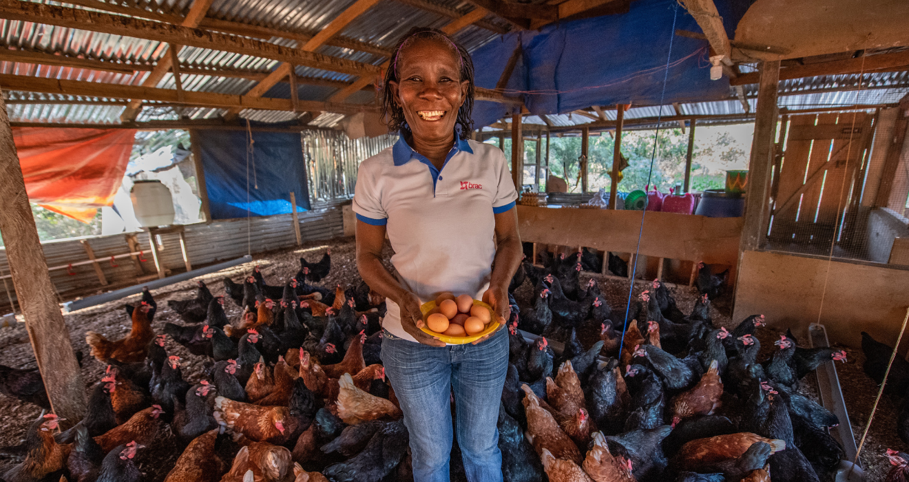 Selena holds a bowl of eggs while standing in her coop full of hens.