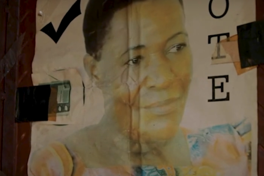 An image of Mary's face can be seen on a poster reading "Vote" with a checkmark that is hung up on a wall