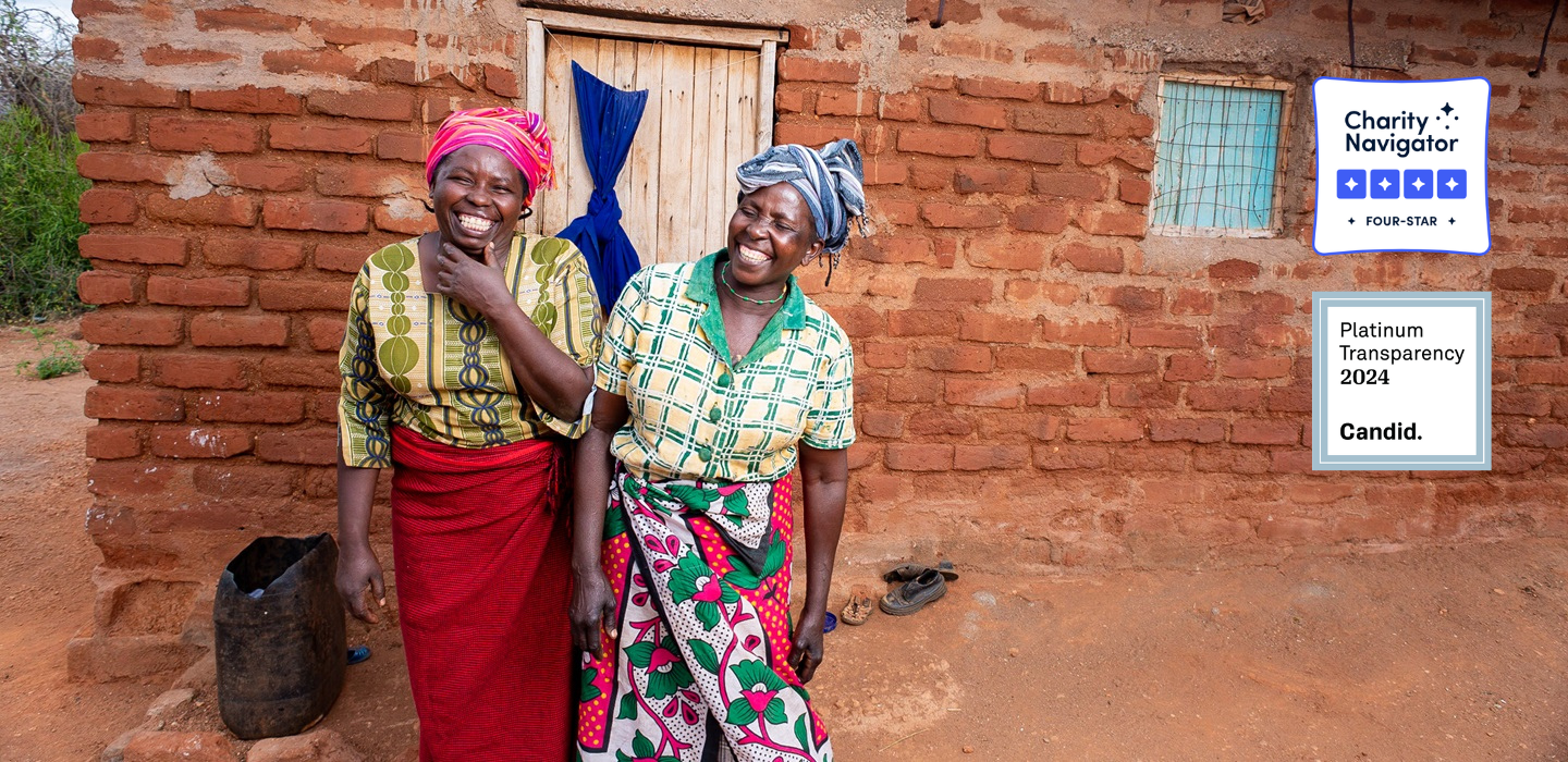 Two women smiling in front of their new brick house