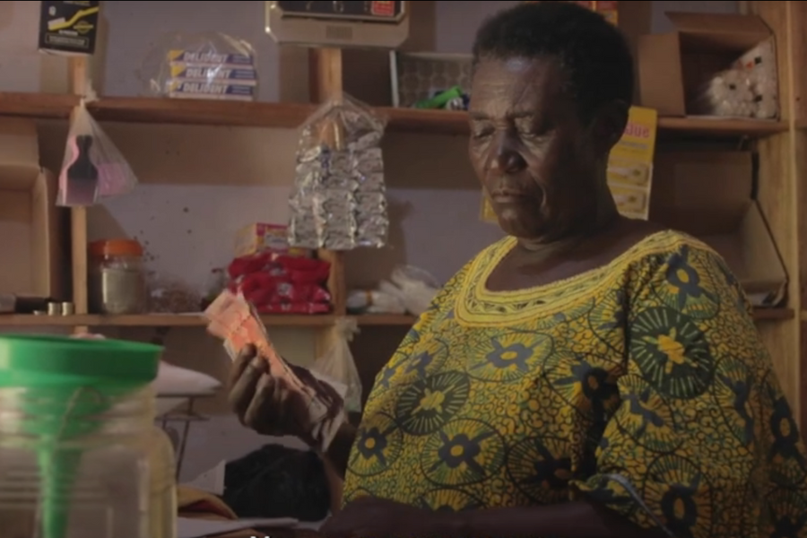 Mary stands in her shop counting cash at the end of the day