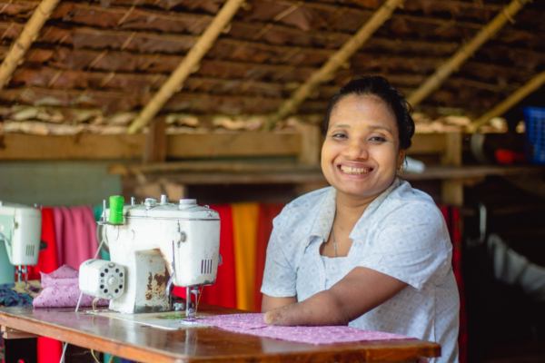 Zin smiles while she sits at her sewing machine.