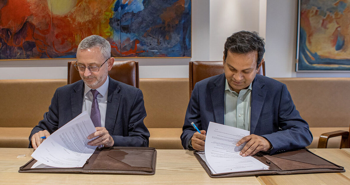 Leaders from BRAC and the European Union sit at a table while signing an agreement.
