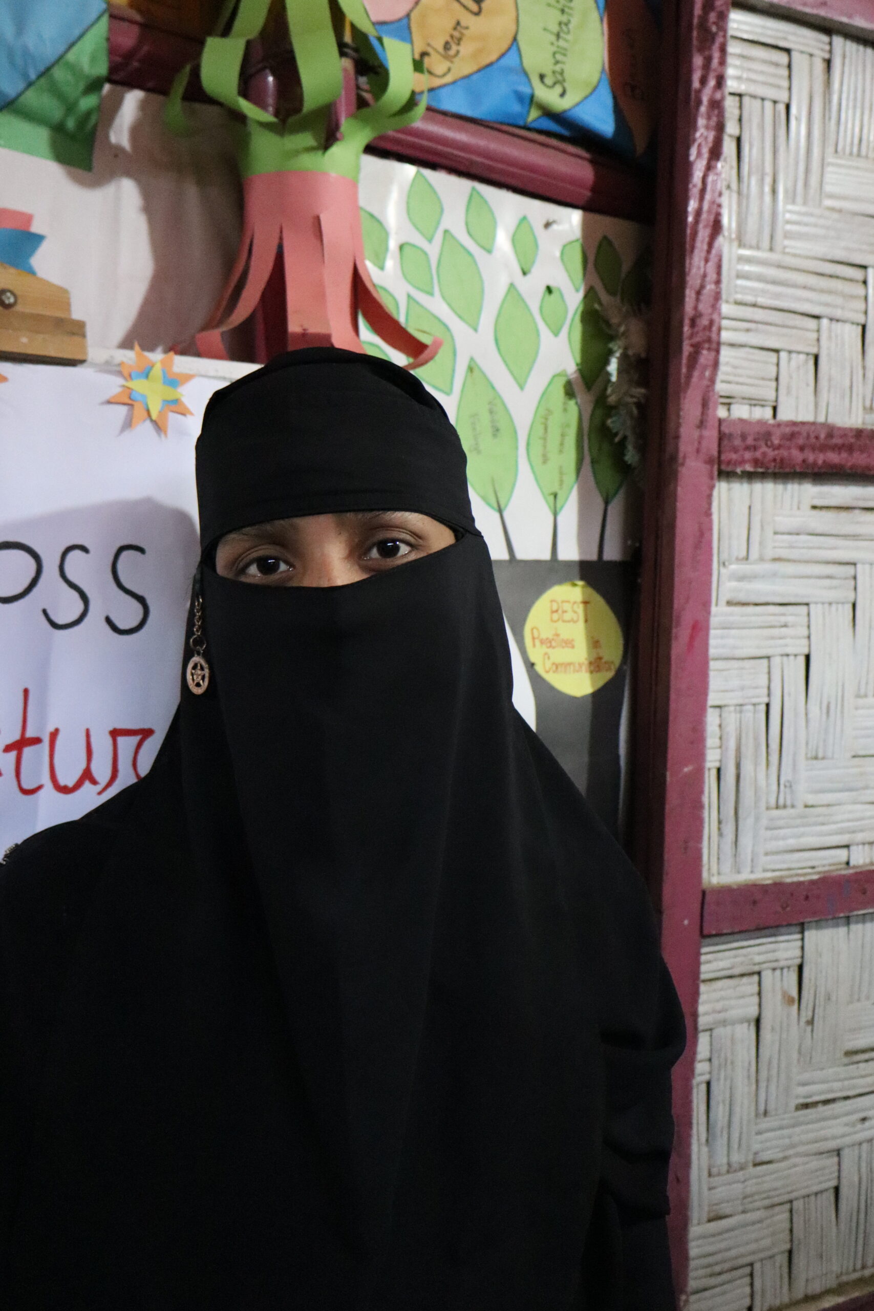 A portrait of a Rohingya woman standing in a safe space.