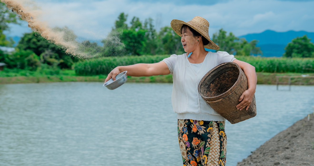 A woman in South Asia holds a basket while water is shown in the background